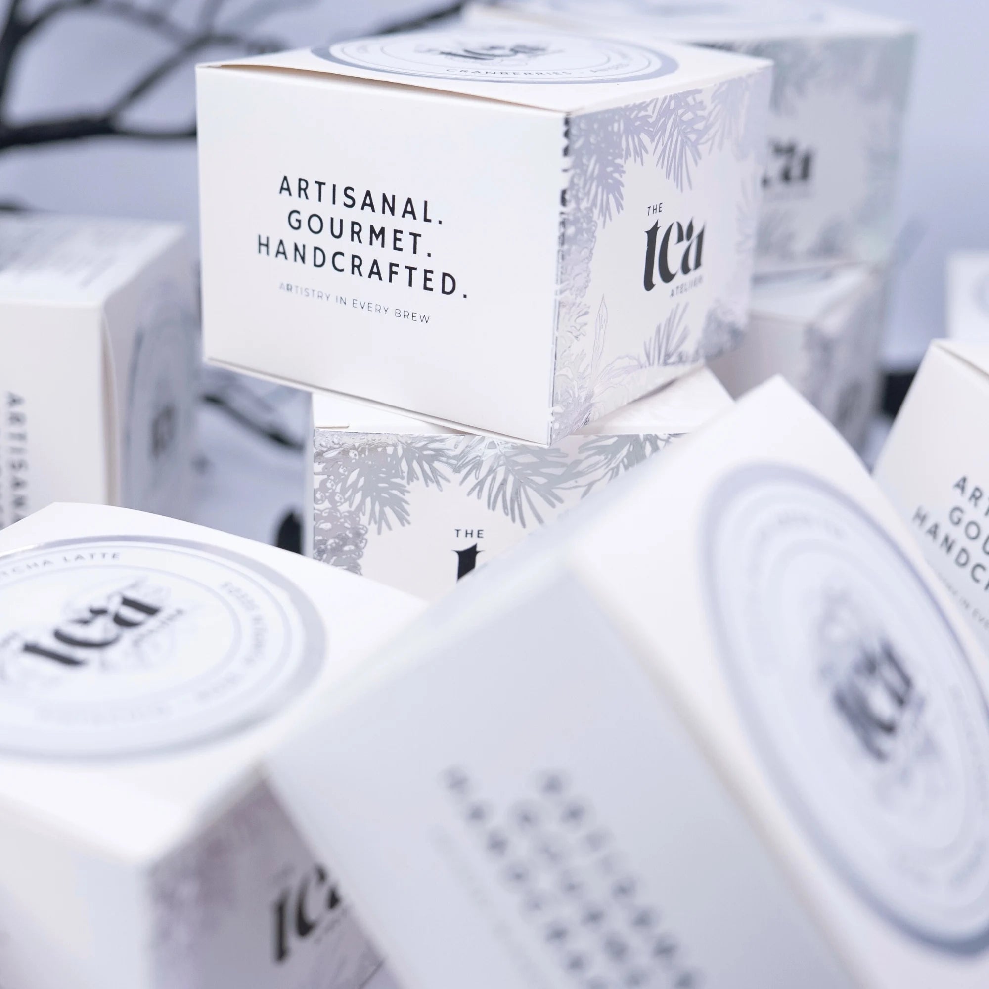 Tea boxes with 'Artisanal Gourmet Handcrafted' text on a blurred background
